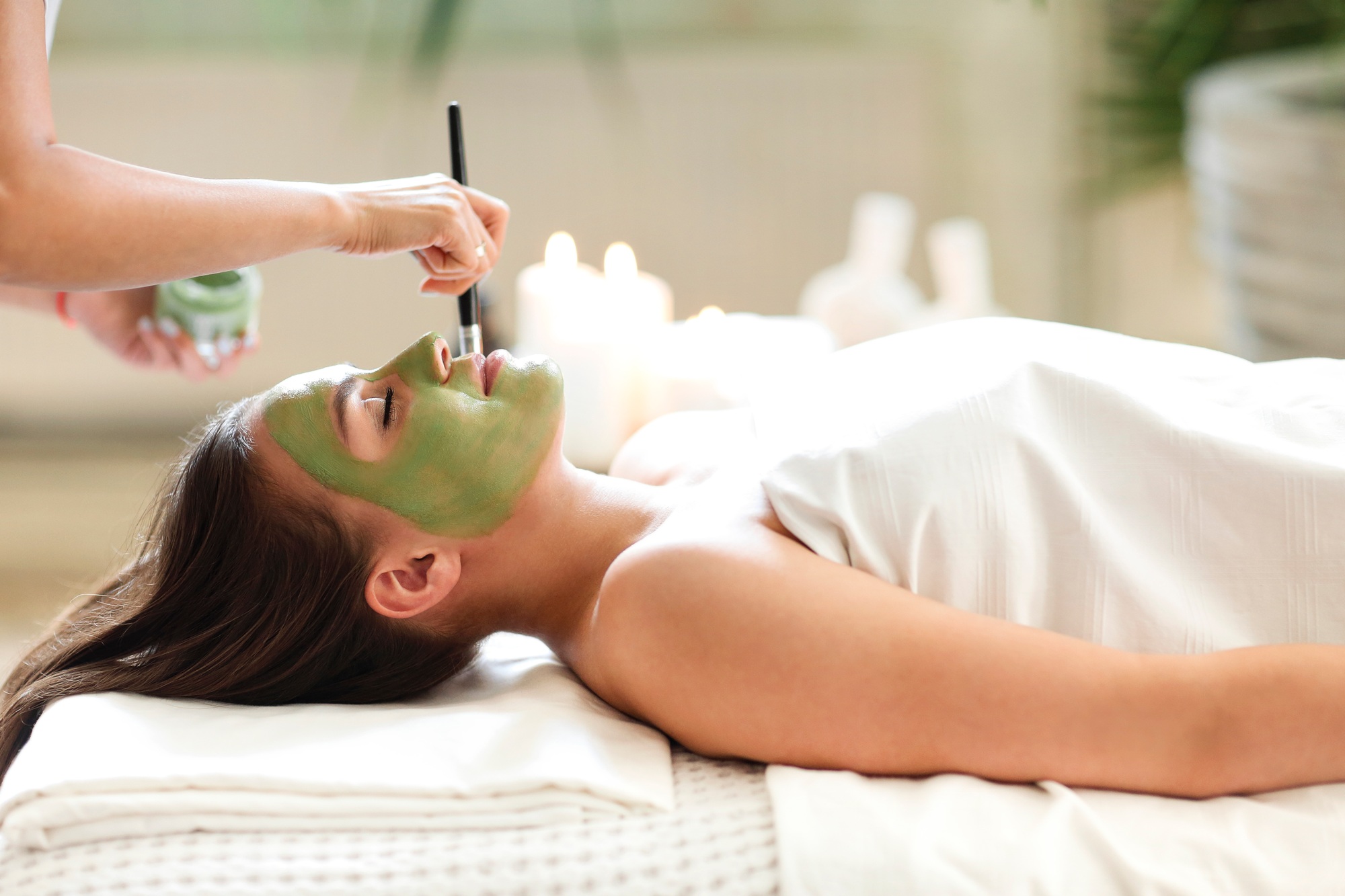 Beautiful relaxed woman having clay face mask