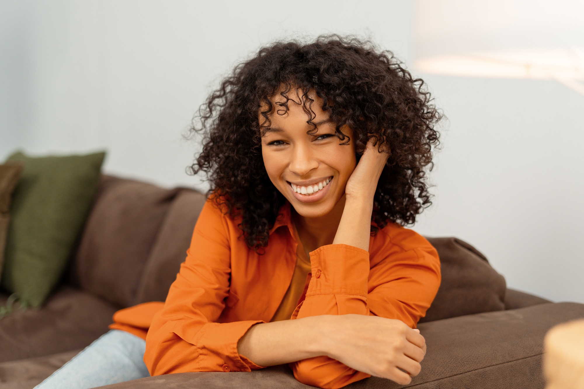 Portrait beautiful smiling African American woman with curly hair sitting on comfortable sofa