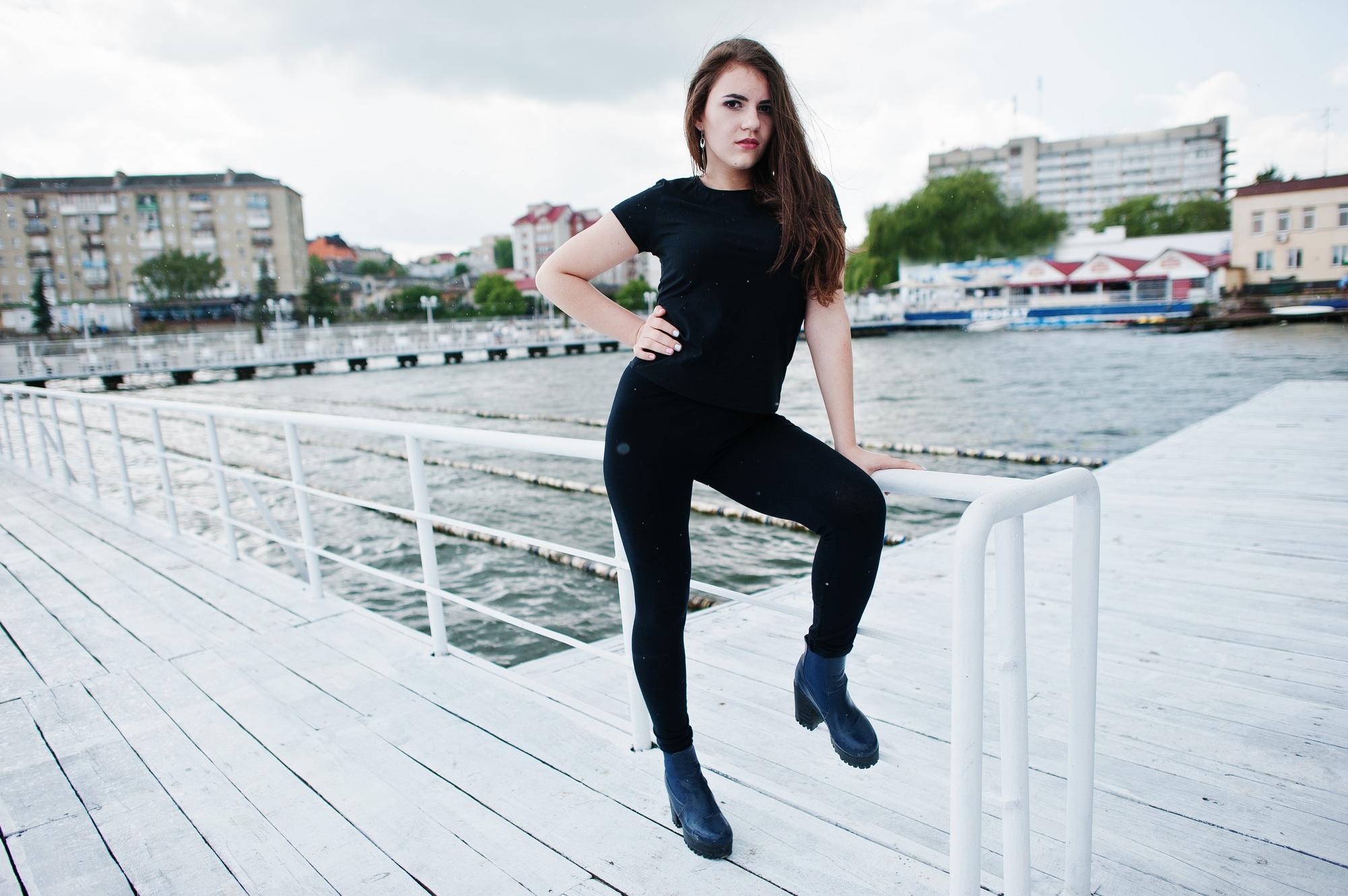 Young girl at black clothes posed on the pier